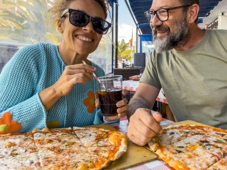 Téléchargez les photos : Réunions dans une pizzeria. Beau couple souriant appréciant la pizza, s'amusant ensemble. Consommation, alimentation, mode de vie concept - en image libre de droit