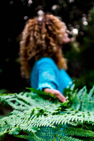 Téléchargez les photos : Concept d'environnement et de sauver la planète Terre avec un gros plan de feuilles vertes tropicales et la femme en arrière-plan - la nature et les soins de la forêt en plein air pour les gens aime le plein air - en image libre de droit