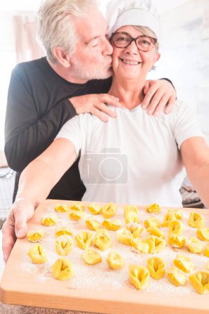 Photo for Happy senior people enjoying home indoor activity cooking italian tortellini healthy hand made Tortellini food - concept of lockdown stayhome people for coronavirus pandemic emergency - Royalty Free Image