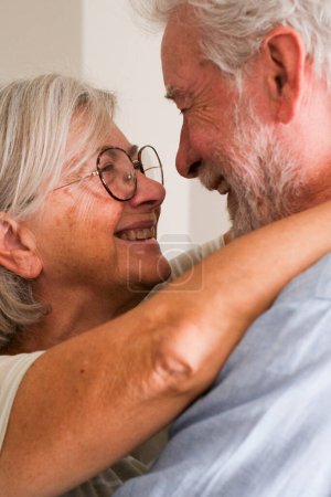 Les personnes âgées aiment les couples matures caucasiens qui se câlinent et se regardent les yeux souriants et aimants dans leur relation. Senior homme et femme coller et profiter d'une activité de loisirs d'intérieur avec romance