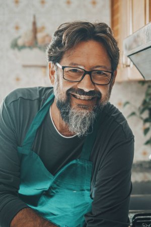 Photo for Portrait of man housekeeper looking on camera happy smiling and cleaning the kitchen at home. Single male people lifestyle. Housework person. Cheerful husband helping wife in housework clean job - Royalty Free Image