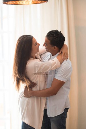 Photo for Romantic couple at home. Attractive young woman and handsome man are enjoying spending time together. Passionate couple is dancing on light modern room with happiness and love. Happy lifestyle people - Royalty Free Image