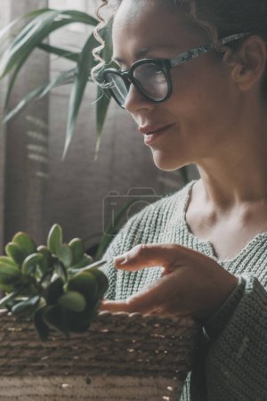 Photo for Adult woman relaxing at home in indoor gardening leisure activity alone with green succulent plants. Smiling expression portrait female people and nature concept lifestyle. House garden inside - Royalty Free Image