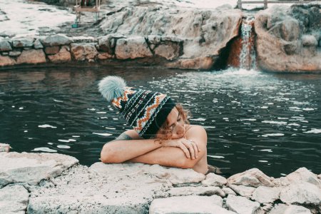 Relax and lifestyle with natural free geothermal hot water spa.  woman relaxing inside thermal spa in outdoors. Winter season. Mountains in background.  Alternative tourism people travel life