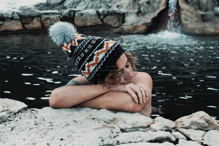 Foto de Relaxed female people tourist enjoy warm volcanic natural pool spa water thermal activity with winter hat. Concept of wellness and body skin care. Nature healthy lifestyle. Woman enjoying relax day - Imagen libre de derechos