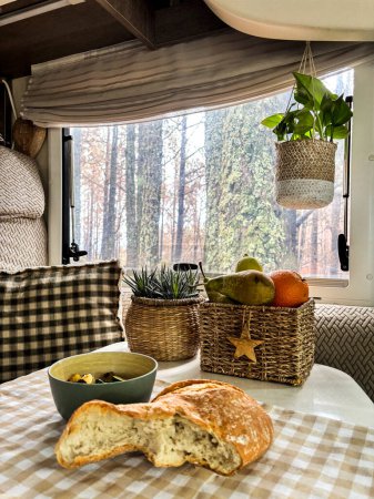 Photo for Interior of camper van motorhome with food on the table and forest view outside the window. Concept of vanlife and travel people vacation lifestyle - Royalty Free Image