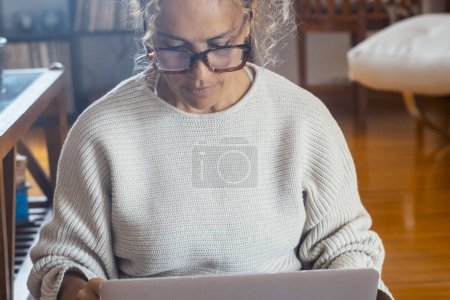 Photo for Adult woman working on laptop alone at home sitting on the wooden floor. Wireless connection and technology. Female modern people using computer to search the web and go shopping online internet - Royalty Free Image