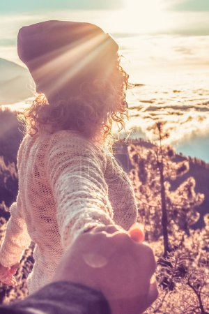 Photo for Adult woman hold the hand of her boyfriend and enjoy the sunset at the mountains in hiking outdoor leisure activity - people in the nature have fun together - alternative vacation - Royalty Free Image