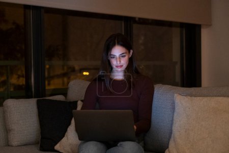 Porträt einer jungen glücklichen Frau mit Laptop in der Nacht, mit moderner Technologie Spaß mit glühendem Bildschirm im dunklen Büro oder zu Hause, Start-up-Business-Meeting online mit Geschäftsfrau