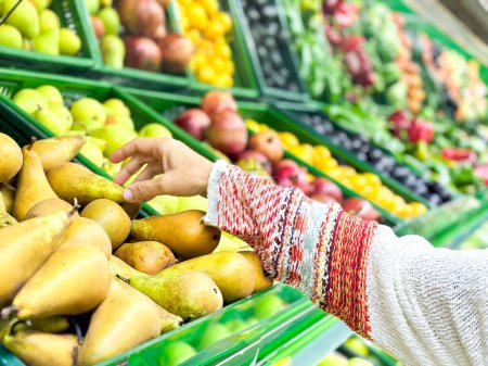 Téléchargez les photos : Gros plan mains féminines prenant des fruits au marché, belle, jolie jeune femme en pull ramasser, en choisissant des légumes verts à feuilles dans l'épicerie - en image libre de droit