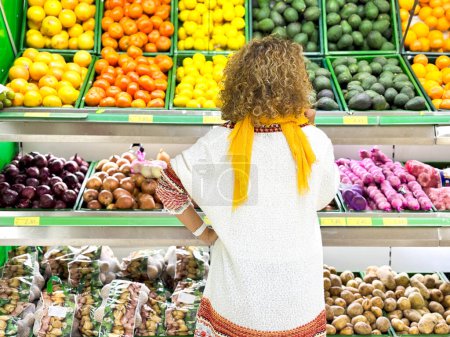 Téléchargez les photos : Belle jeune femme faisant du shopping pour les fruits et légumes dans le département des produits d'une épicerie / supermarché (image tonique de couleur) - en image libre de droit