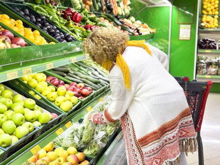 Foto de Retrato de primer plano, hermosa, bonita mujer joven en suéter recoger, la elección de verduras de hoja verde en la tienda de comestibles - Imagen libre de derechos