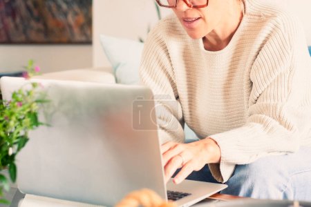 Photo for Satisfied adult woman relaxing on comfortable couch, using laptop at home, happy lady chatting with friends in social network, spending lazy weekend, watching movie, shopping online, writing email - Royalty Free Image