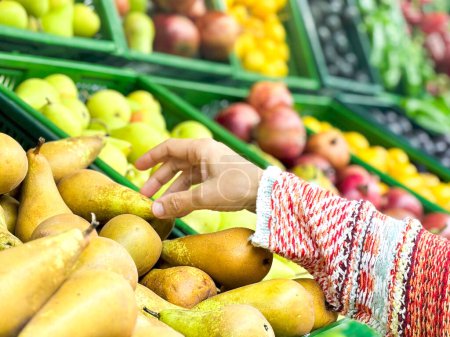 Téléchargez les photos : Gros plan main féminine prenant des fruits au marché, belle, jolie femme en pull ramassant, choisissant des légumes verts à feuilles dans l'épicerie - en image libre de droit