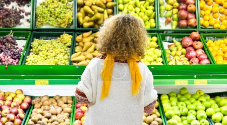 Foto de Vista trasera de rizado Hermosa mujer de compras de frutas y verduras en el departamento de productos de una tienda de comestibles / supermercado (color tonificado imagen) - Imagen libre de derechos
