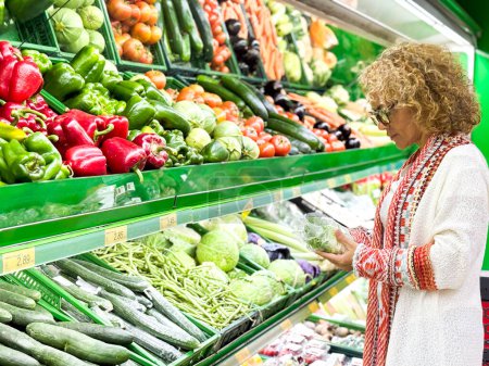 Téléchargez les photos : Gros plan portrait, belle, jolie femme en pull ramassant, choisissant des légumes verts à feuilles dans l'épicerie - en image libre de droit