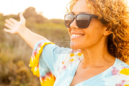 Photo for Cheerful happy woman having fun and enjoying outdoor leisure activity alone smiling and enjoying outdoor leisure activity alone wearing sunglasses for sun. People and healthy lifestyle concept - Royalty Free Image
