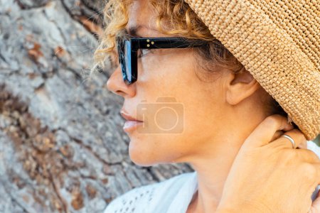 Téléchargez les photos : Portrait d'une femme attirante adulte dans une activité de loisirs de plein air se détendre et porter des lunettes. les femmes ont le temps de se détendre et sourire avec le tronc en arrière-plan. Touristes et voyageurs - en image libre de droit