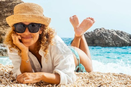 Touristin liegt am tropischen Strand und genießt die Freizeitaktivität im Freien allein und mit Strohhut. Menschen und Lebensstil im Sommerurlaub. Erwachsene Frauen lächeln in landschaftlich reizvoller Umgebung