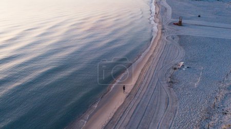 Foto de Imagen tomada desde arriba de la playa de verano y mar azul claro y turquesa Imagen tomada desde arriba de la playa de verano y mar azul claro y turquesa. Hombre caminando en la orilla - Imagen libre de derechos