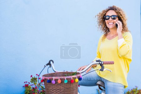 Téléchargez les photos : Vélo, charmante femme en ville se sent sereine et détendue tout en parlant au téléphone à l'air mignon. Des transports respectueux de l'environnement pour réduire l'empreinte carbone des femmes qui font du vélo - en image libre de droit