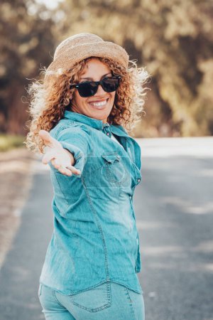 Photo for Portrait of wonderful  female model with curly blonde hair expressing energy on a good day in Europe. Beautiful curly woman smiling and walking with trees behind her. - Royalty Free Image