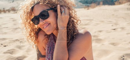 Foto de Retrato de una mujer sentada en la arena relajada y serena. Turista sonriente en la playa disfrutando de vacaciones. - Imagen libre de derechos