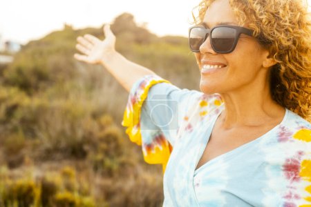 Photo for Cheerful happy woman having fun and enjoying outdoor leisure activity alone smiling and enjoying outdoor leisure activity alone wearing sunglasses for sun. People and healthy lifestyle concept - Royalty Free Image