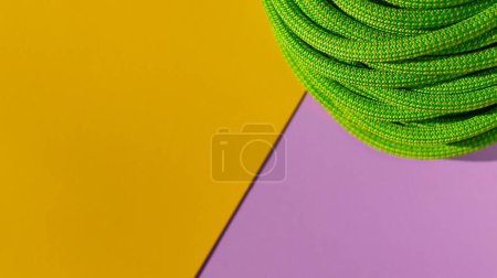 Photo for Green rope for rock climbing and mountaineering lies on a colored background. background image of rope for active sports. sports equipment. - Royalty Free Image