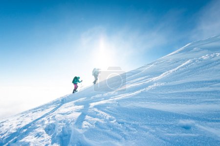 climbing a snow-covered mountain, two women in winter trekking, climbers climb to the top of the mountain in winter