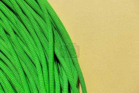 Photo for Green rope for rock climbing and mountaineering lies on a yellow background. ropes for active sports. sport equipment. - Royalty Free Image