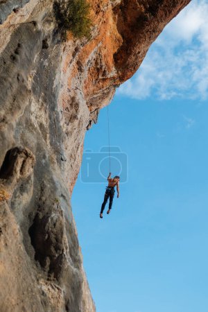 Photo for Rock climber descends from a route, a climber hangs on a rope against the sky, rock climbing routes in a cave, a man rappels down a rope - Royalty Free Image