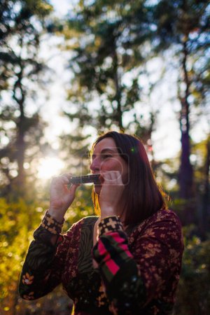 Photo for Young girl plays the harmonica in the forest. the girl loves to play the harmonica. girl in the forest. - Royalty Free Image