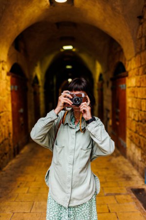 Fotografin mit Kamera fotografiert im Freien. Eine junge Fotografin zielt auf das Objektiv und genießt den Aufnahmeprozess. Reisen in arabische Länder. Reisen und Urlaub.