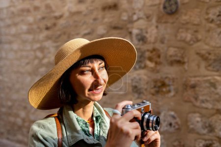 Hermosa mujer en un sombrero toma fotos al aire libre utilizando una cámara analógica. viajar a los países árabes. viajes y vacaciones.