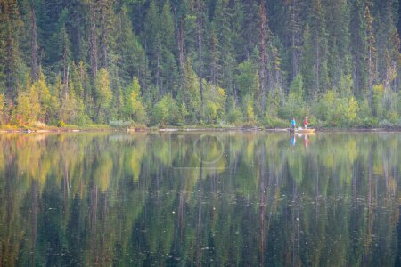 dos hombres en un pequeño barco en un hermoso lago tranquilo de pesca