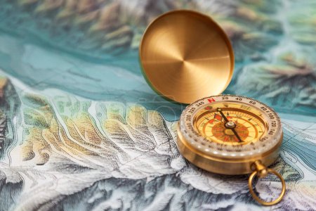 Photo for Close-up of a vintage gold compass on a map. Focus is centered on the compass north indicator, the rest is out of focus. - Royalty Free Image