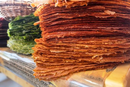 Foto de Pile of Tklapi - traditional georgian pastila or fruit leather. Colorful dried mushed fruit sheets sold at food market for tourists. Delicious and healthy Georgian and Armenian sweet dessert. - Imagen libre de derechos