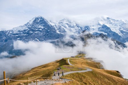 Téléchargez les photos : Automne dans les Alpes suisses. Sentier pédestre au sommet de Mannlichen près de Wengen et Lauterbrunnen, Suisse. Chaîne de montagnes avec sommets Eiger, Monch, Jungfraujoch et Jungfrau dans les nuages bas. - en image libre de droit