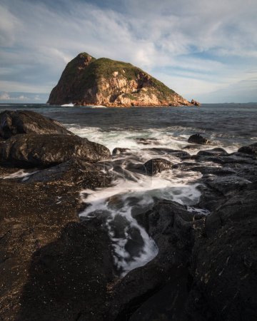 Foto de Agua que fluye en las rocas cerca de la isla grande en el océano - Imagen libre de derechos