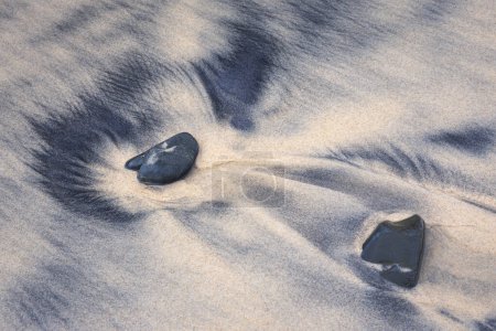Felsen in weißem und schwarzem Sand am Strand von Diggers Camp NSW Australia