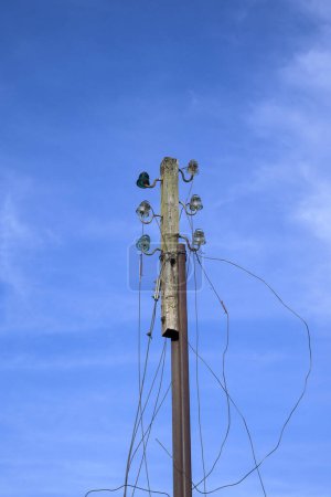 Foto de Poste telefónico viejo en desuso con cables cortados con cielo azul en vertical - Imagen libre de derechos