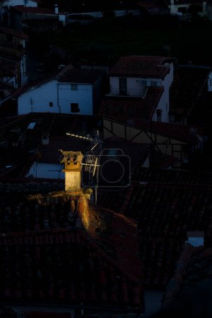 Foto de Antigua chimenea en el techo junto a la antena de televisión iluminada al atardecer - Imagen libre de derechos