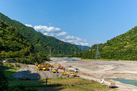Limpiar el lecho del río en las montañas, equipo de construcción, excavadoras y camiones elimina las consecuencias de las inundaciones de primavera de los ríos de montaña.