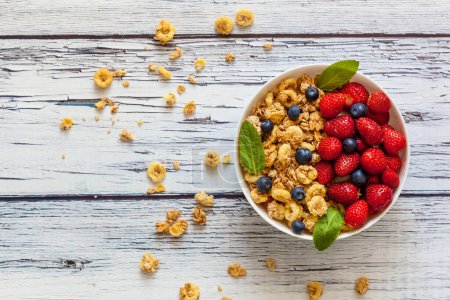Morgens Frühstück mit Haferflocken, Erdbeeren und Blaubeeren in einer weißen Tasse auf einem Holztisch