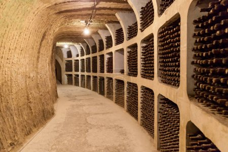 Foto de Viejas botellas de vino apiladas en hileras en las bodegas de una bodega - Imagen libre de derechos