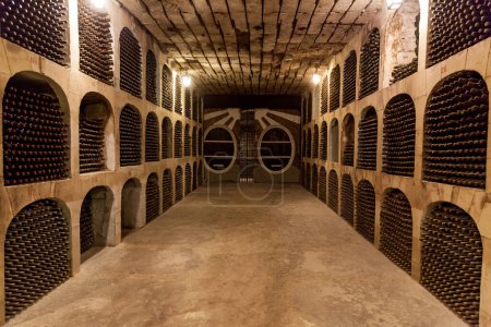 Photo for Old wine cellar with stacks of old wine bottles.Old wine bottles are stacked in rows in the cellars of the winery - Royalty Free Image