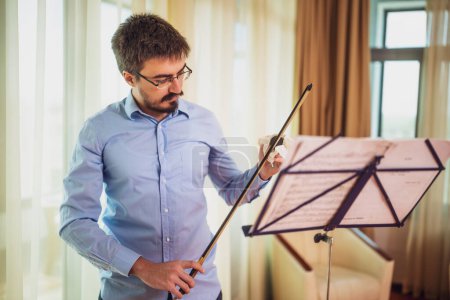 Mann spielt zu Hause Geige. Er koloriert einen Geigenbogen.