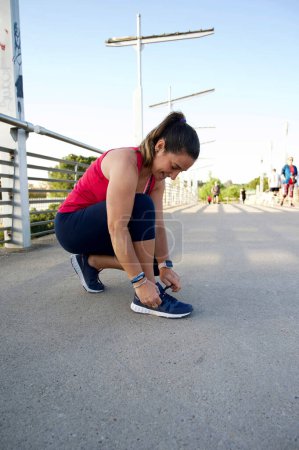 Téléchargez les photos : Femme attachant lacets avant de courir sur le pont urbain - en image libre de droit