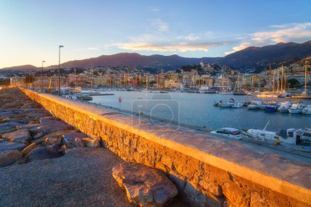 Panoramic view of Sanremo or San Remo from the sea, Italian Riviera, Liguria, Italy. Scenic sunset landscape with city architecture, seafront, mountains, blue water and sky, outdoor travel background